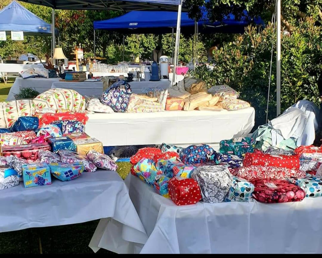 Market stalls - tables under marquees with a range of brightly coloured wrapped parcels on the tables for the pick a parcel stall.