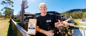 Brisbane Valley Roasters Owner - Nick standing out the front of the cafe throwing coffee beans in the air.