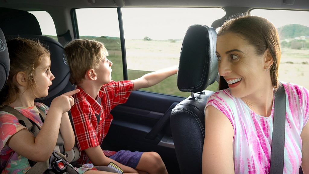 A family smiling in a car.