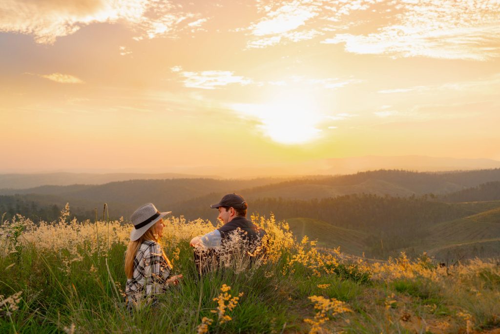 Couple watching the sunset over Jimna whilst sitting in the grass.