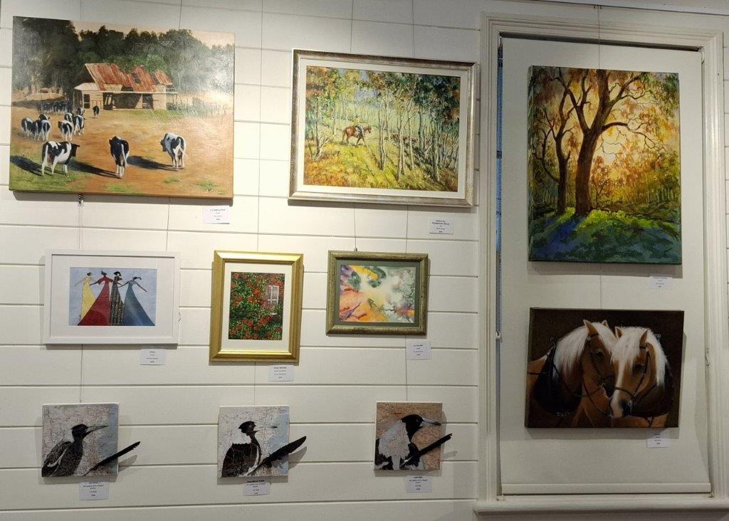 Photo of a range of different sized and coloured paintings on a wall at the Kilcoy Courthouse Art Gallery.