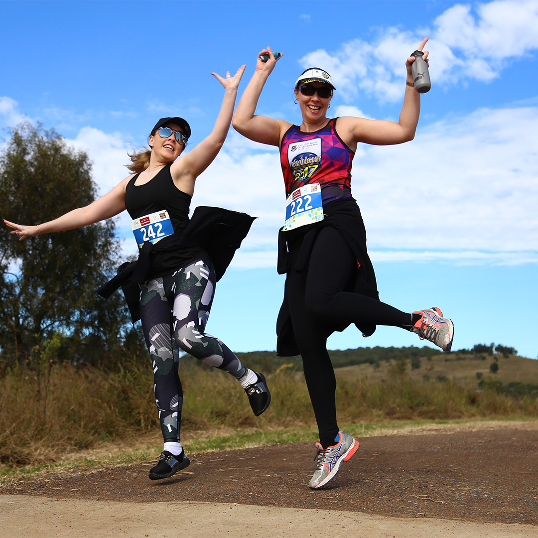 Two ladies in active wear happy jumping during the Somerset Rail Trail Classic run