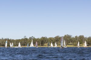 Sailing boats on Lake Wivenhoe. Blue skies and blue lake with a tree lined shore in the background.