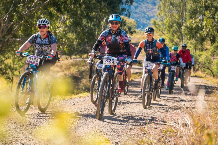 A group of cyclist ride across a rocky driveway