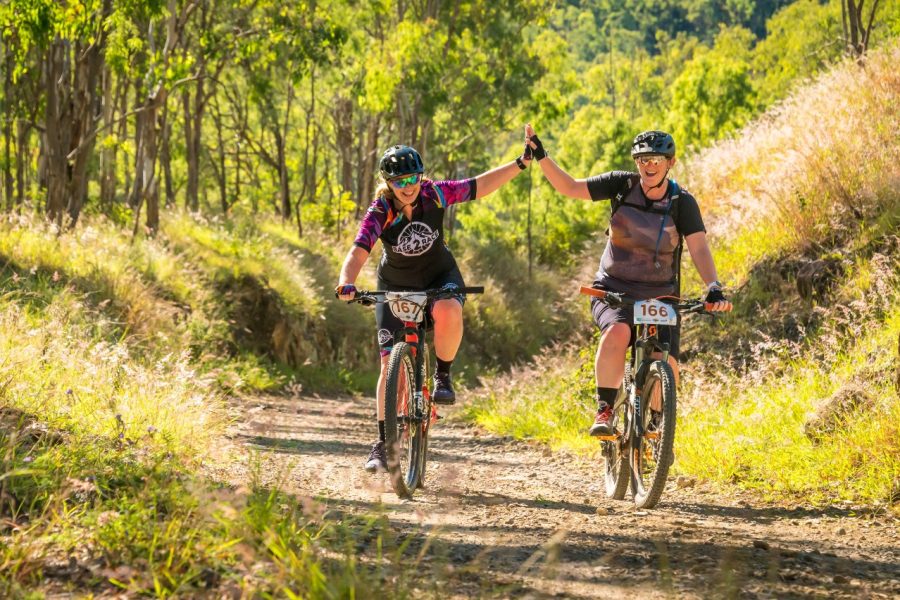 Two cyclists high five mid ride on BVRT