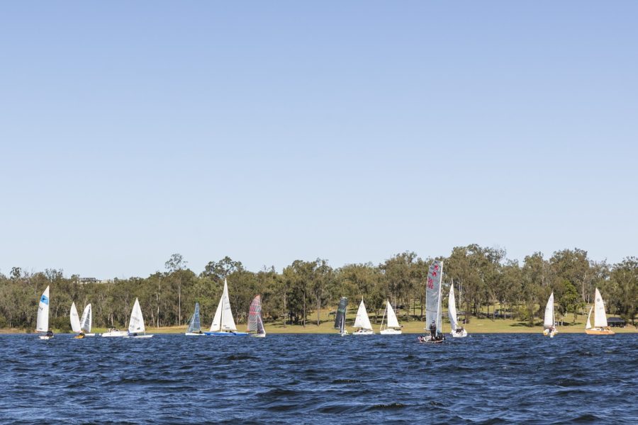 Sailing boats on Lake Wivenhoe. Blue skies and blue lake with a tree lined shore in the background.