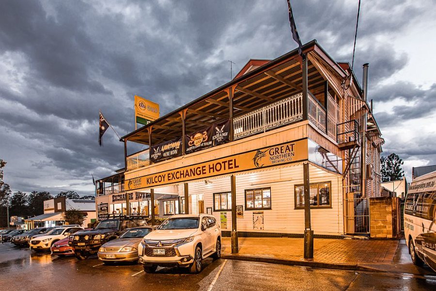 The Exchange Hotel Kilcoy, front of the building in the early evening. Its a two story building with cars parked out the front (reversed in). It looks like it has been raining with grey clouds in the background.