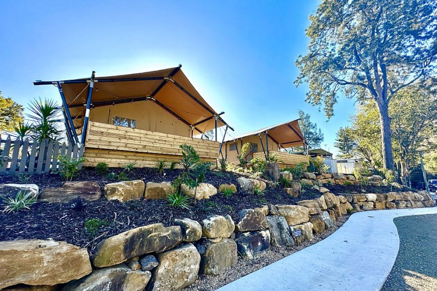 Glamping tents at the Esk Caravan Park. Looking up at the Glamping canvas tents from the walkway below, with blue sky and trees surrounding them