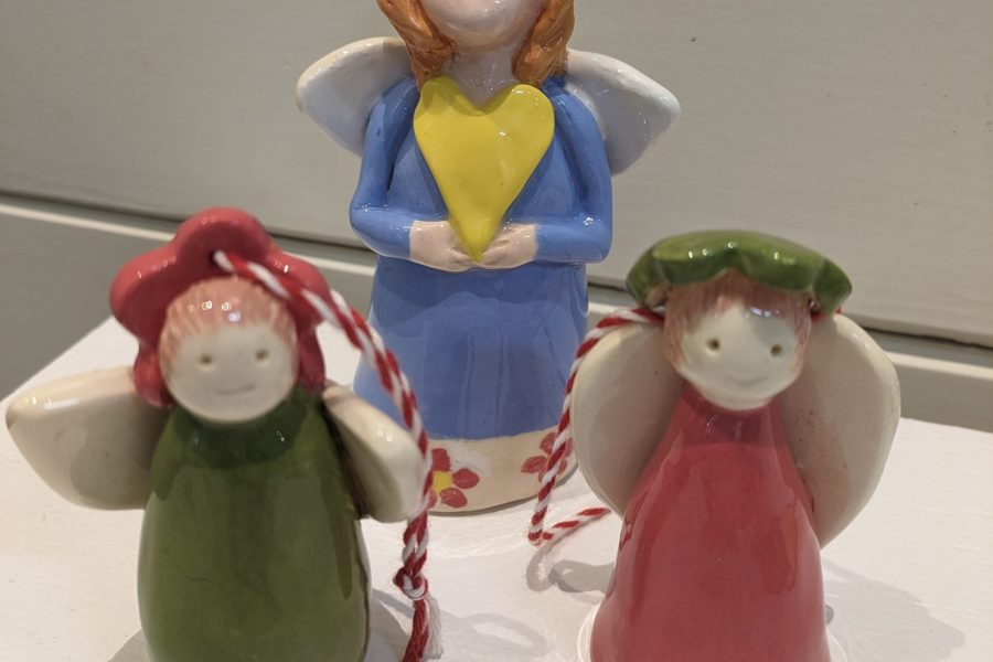 Photograph of 3 Christmas pottery angels with a white wall background.