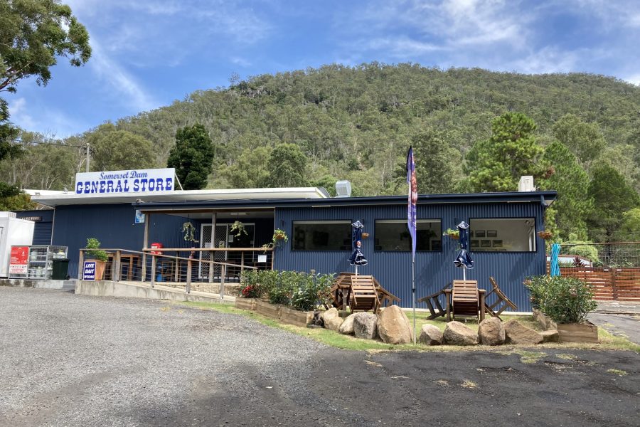 Somerset Dam General Store. Blue building in front of a green mountain and blue sky.