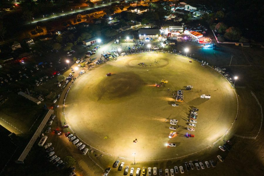 Drone shot of a showgrounds at night, lit up with utes in the middle of the oval.