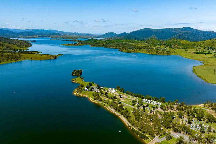 Aerial view of NRMA Lake Somerset Holiday Park, blue sky and lake, with green outcrops of land into the lake