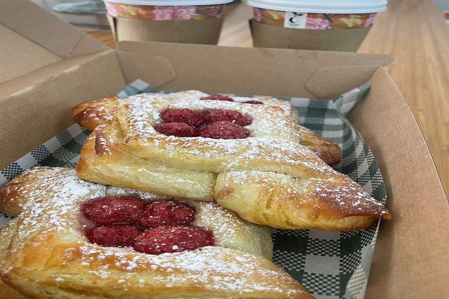 French Pastries (danishes) in a takeaway box, with two takeaway coffee cups in the background.