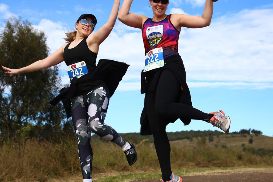 Two ladies in active wear happy jumping during the Somerset Rail Trail Classic run